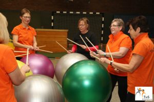 Frauen trommeln auf Gymnastikbällen in der Wirbelsäulengymnastik