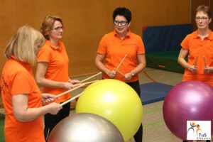 Frauen trommeln auf Gymnastikbällen in der Wirbelsäulengymnastik