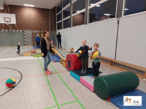 kinderturnen3 Eltern und Kinder beim Turnen in der Sporthalle spielen mit einem Ball