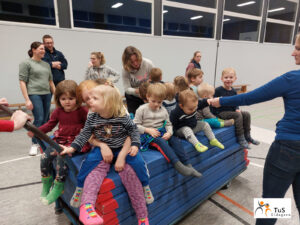 kinderturnen6 Kinder sitzen in der Sporthalle auf dem Mattenwagen