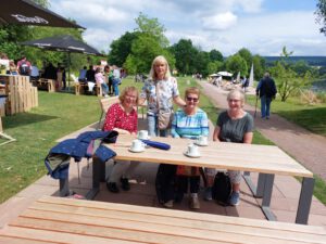 Mehrere Personen sitzen auf einer Band beim Sommerausflug zur Landesgartenschau