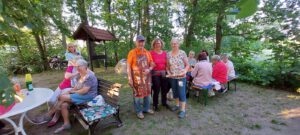 Mehrere Personen sitzen auf einer Bank beim Grillfest am Haller Heideweg