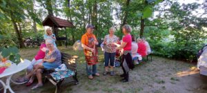 Mehrere Personen sitzen auf einer Bank beim Grillfest am Haller Heideweg